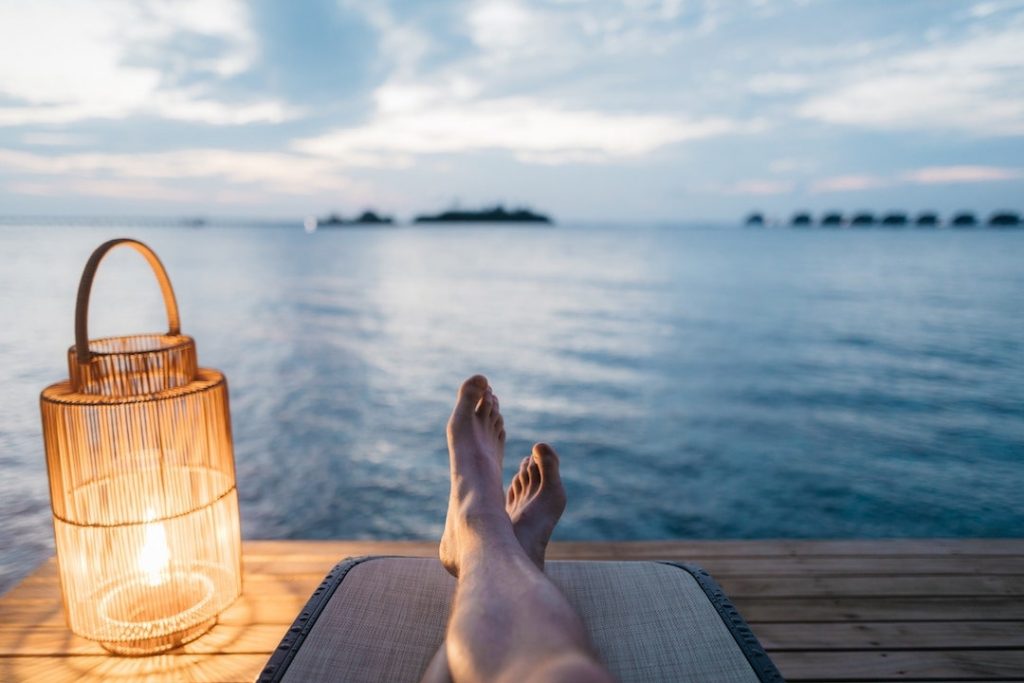 Man laying on a deck with a lantern overlooking water