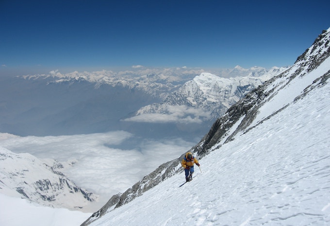 A person in a yellow coat climbing a mountain