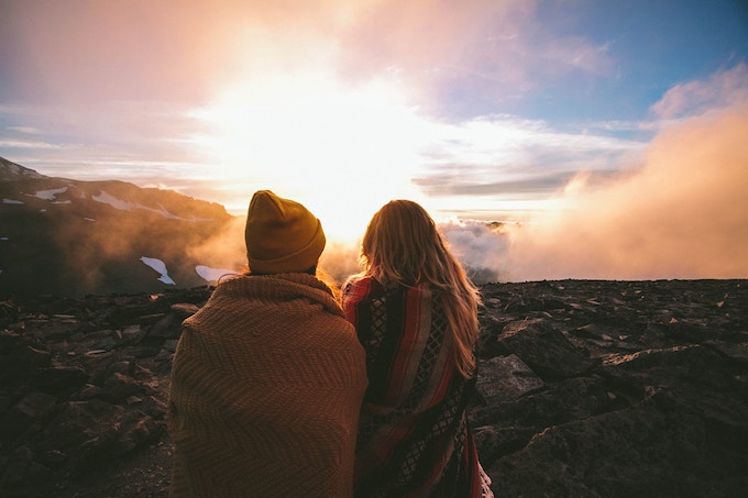 Two girls with blankets around them at sunset