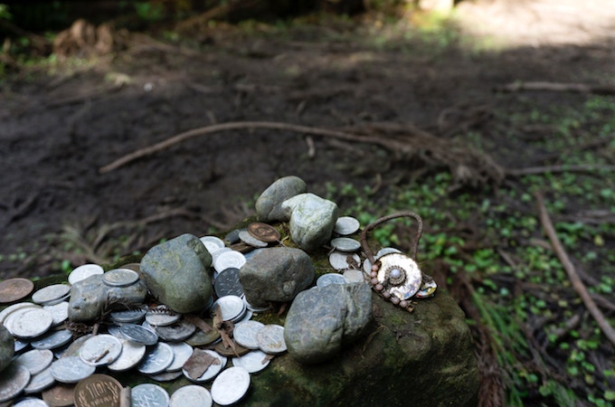 Coins and rocks on a stone along the Kumando Kodo pilgrimage trail in Japan