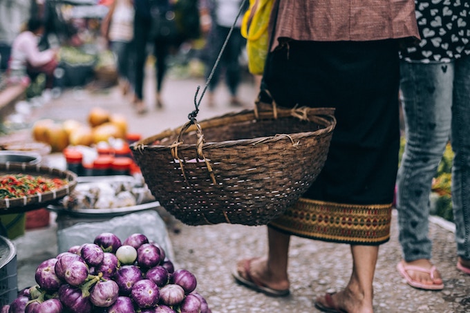 A woman walks through a market in Laos carrying a basket