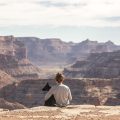 A woman and her dog looking out onto the grand canyon