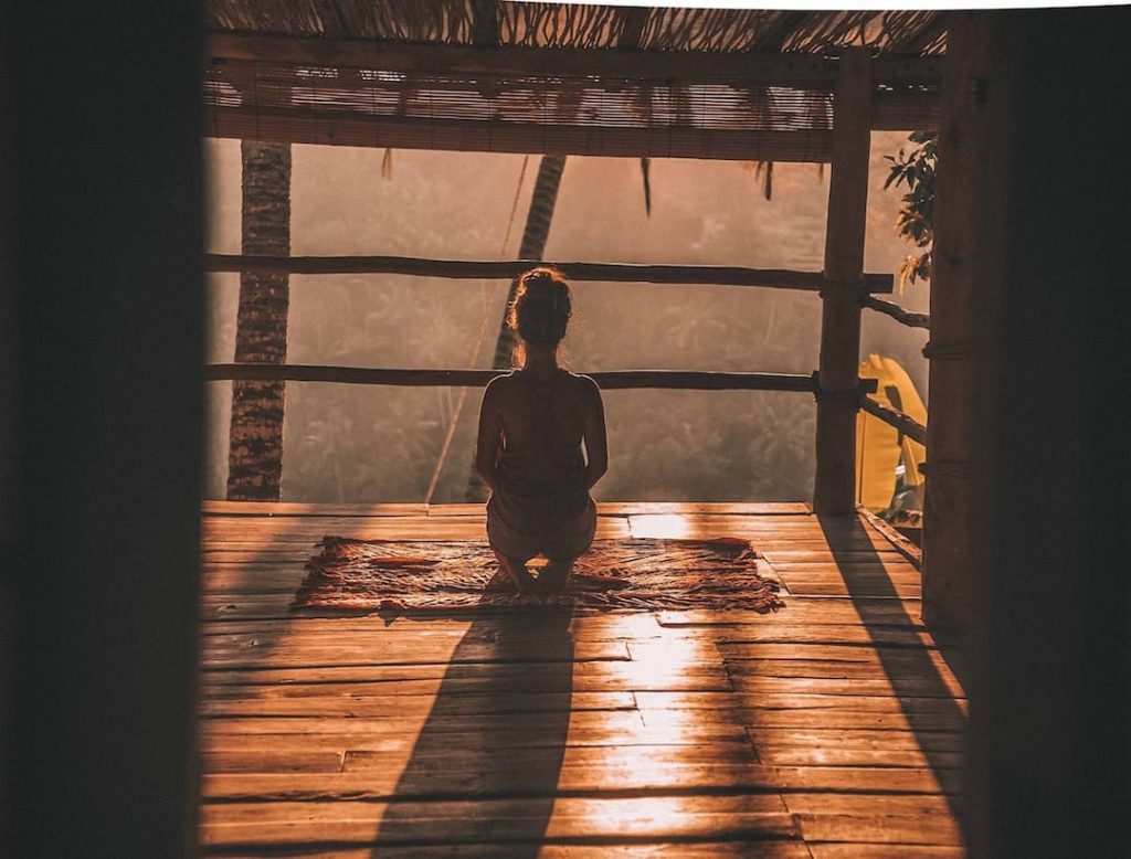 Woman meditating in room over-looking the jungle in Bali, Indonesia