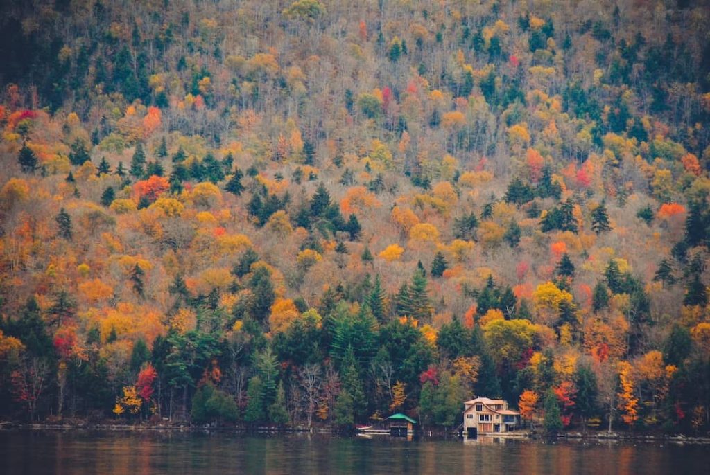 A house on a lake surrounded by fall foliage in the Adirondack Mountains, New York