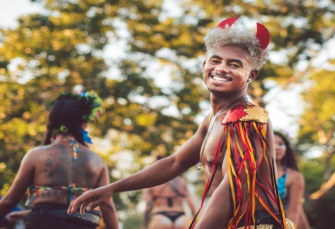 A man with devil horns smiling into the camera during Carnival in Brazil