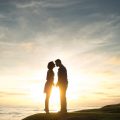 Couple kissing by the ocean at sunset