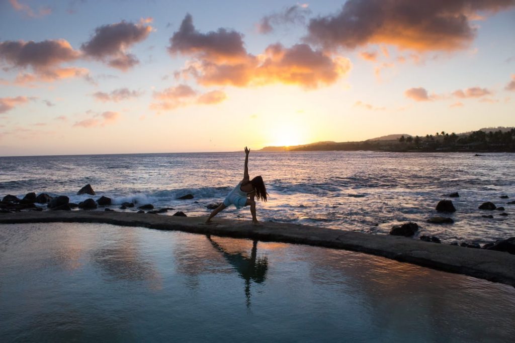 Woman doing yoga on the beach beside the ocean