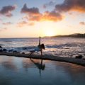 Woman doing yoga on the beach beside the ocean