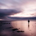 Person standing alone on a beach at sunset