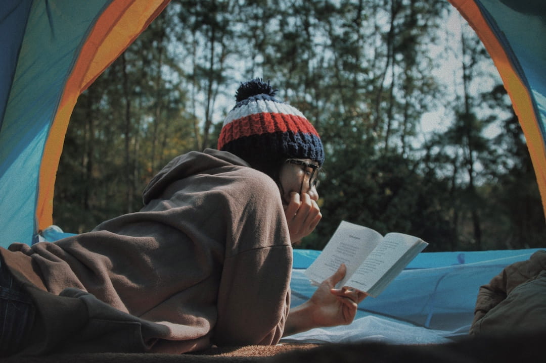 A woman reading while laying in a tent in Vietnam