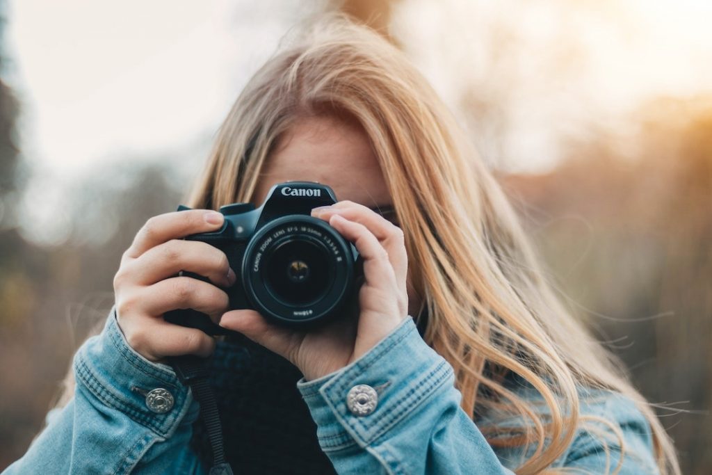 Woman looking through the viewfinder and holding a Canon camera