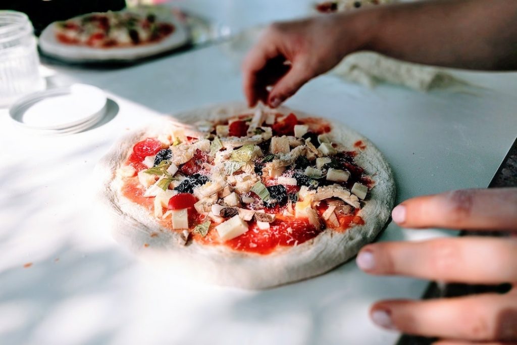 Person making pizza from scratch at a cooking class in Italy