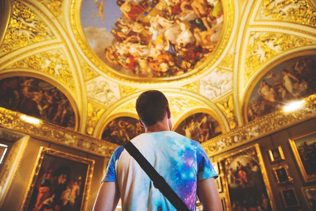 Man looking up at the ceiling in a historic building adorned with frescoes