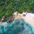 An aerial view of a white-sand beach and forest in Okinawa, Japan