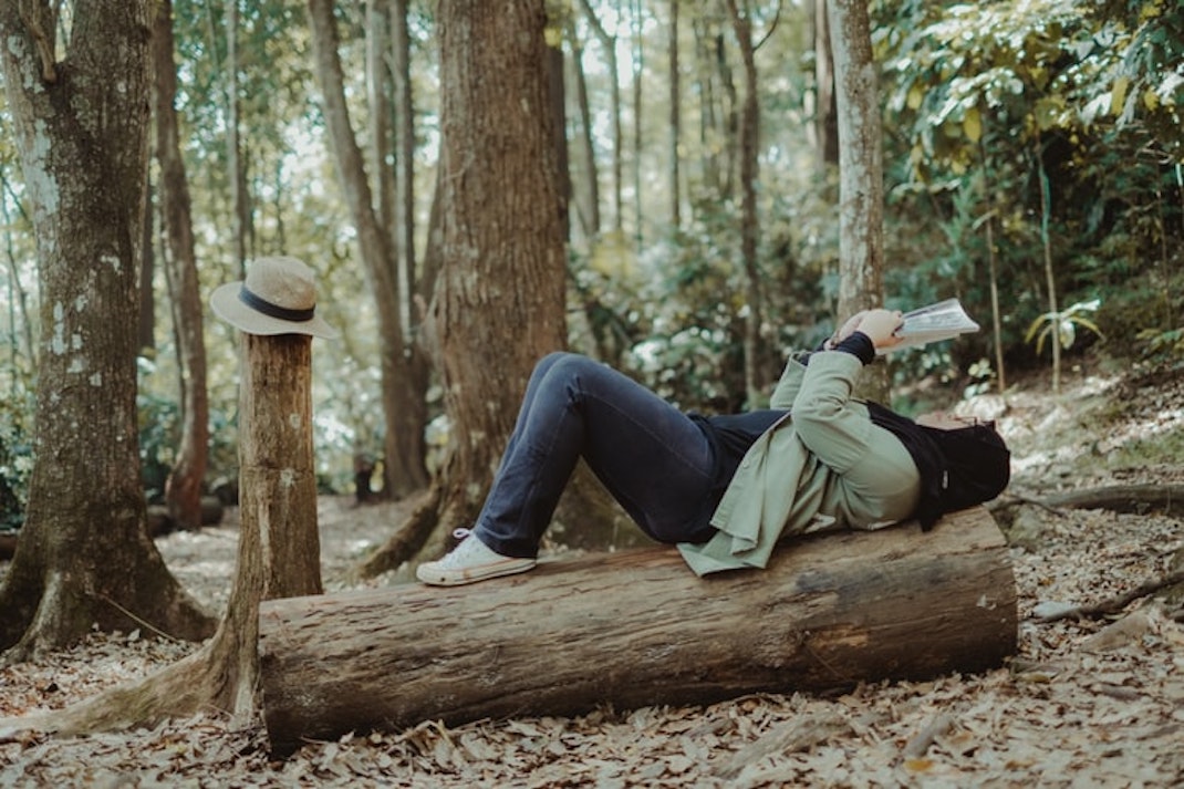 woman lying on a tree trunk reading