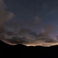 silhouette of mountain under starry sky at sunset