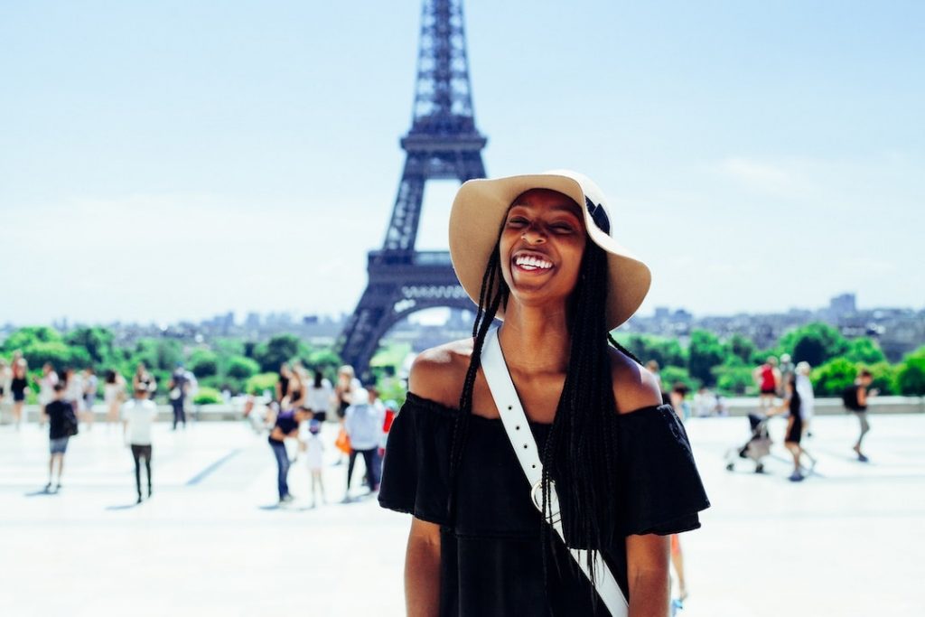 Woman wearing a floppy hat standing in front of the Eiffel Tower in Paris