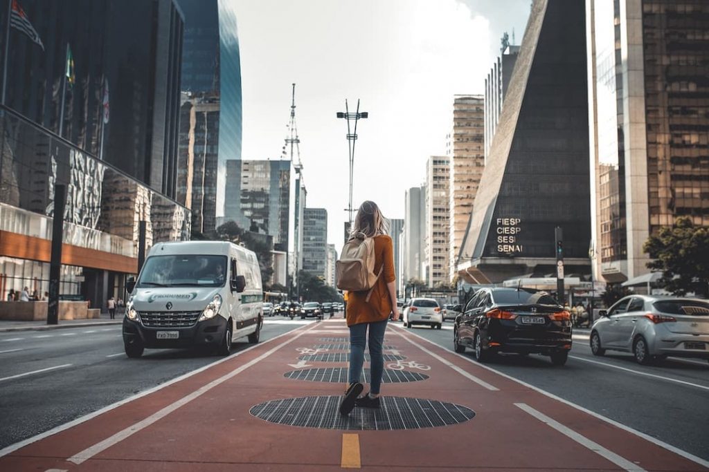 Woman walking down a walkway with traffic on either side in Brazil