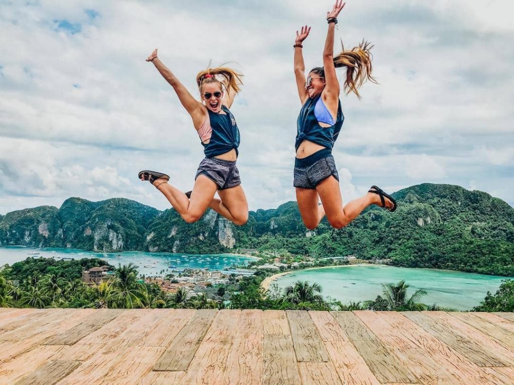 Two women jumping with a bay in the background in Thailand