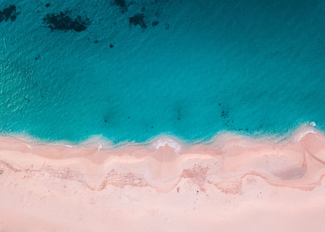 Aerial photo of the ocean meeting the sand on a beach in Australia