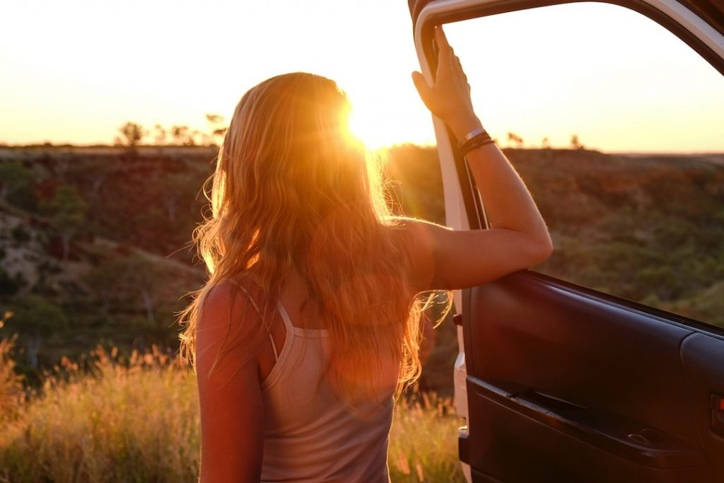 Woman standing on the side of the road with her car door open