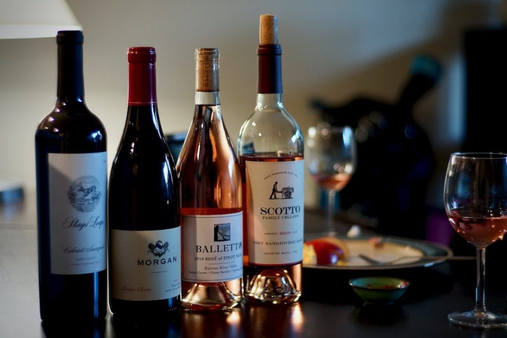 Four bottles of wine on a table with glasses