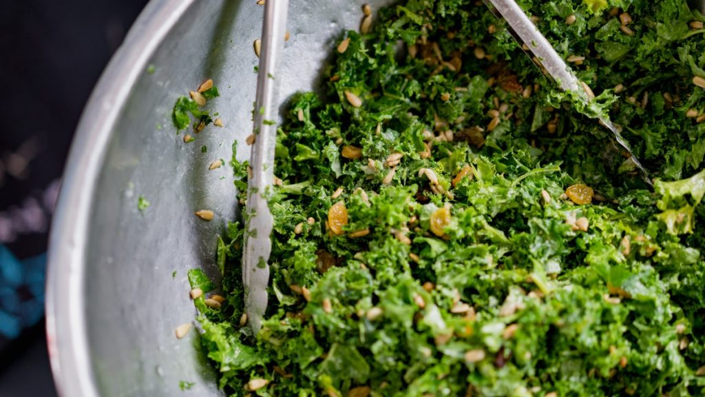 shredded greens and yellow raisins in a bowl