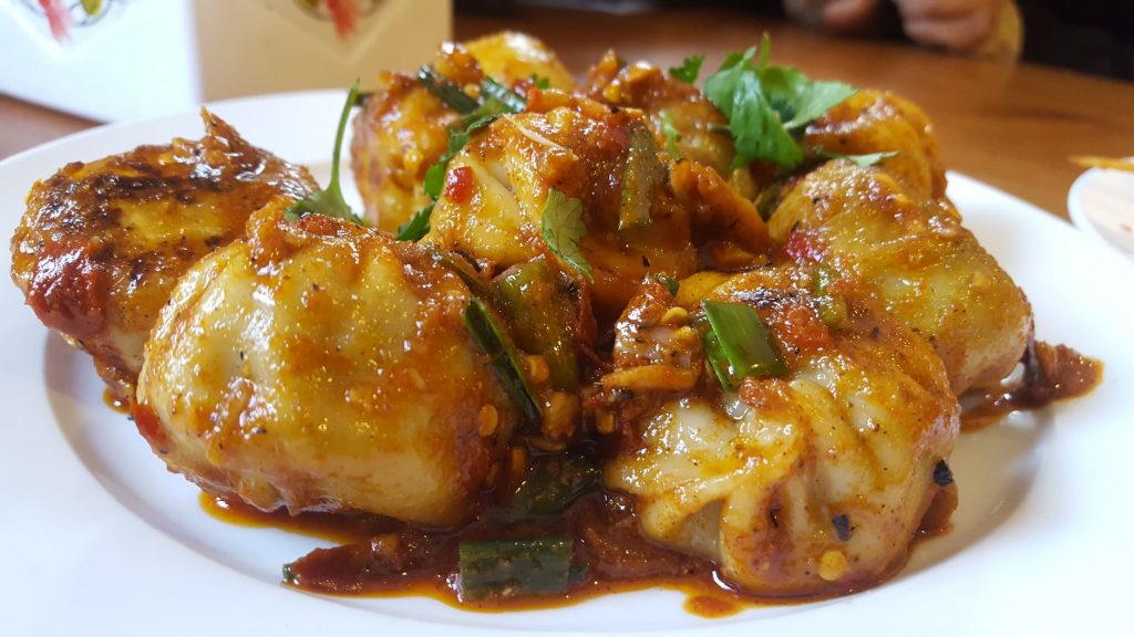 a plate steamed dumplings covered in sauce