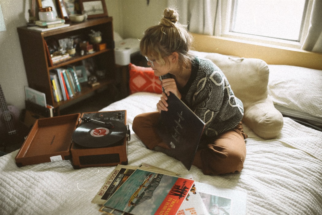 a woman sitting on her bed listening to music