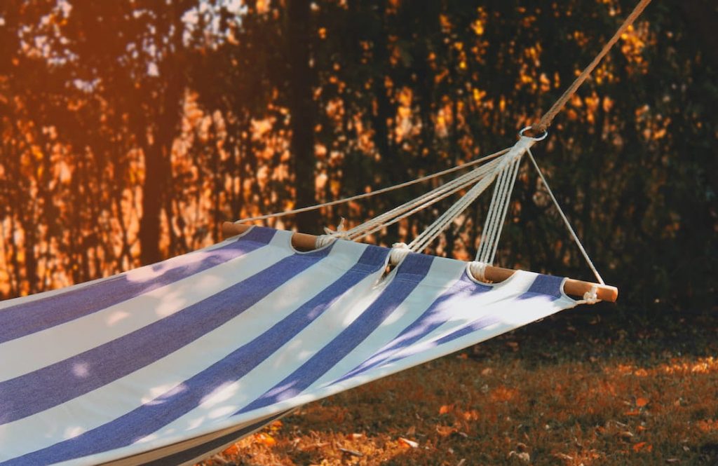 Blue and white striped hammock hanging in a yard