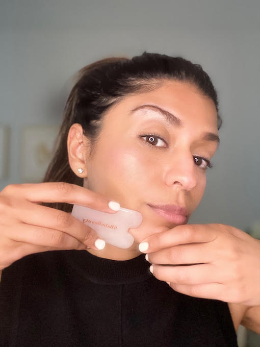 a woman uses a facial tool to sculpt her skin