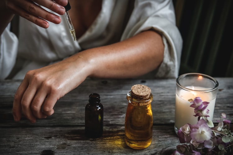 a woman puts a drop of oil on her arm