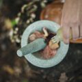 Person pouring oil into a mortar and pestle filled with rose petals