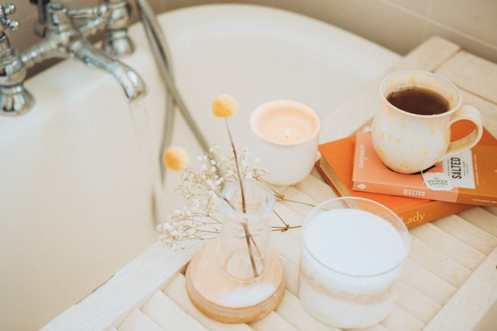 Bath tray with candles, flowers, and a cup of tea