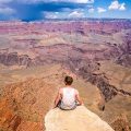 Man sitting on a ledge overlooking the Grand Canyon