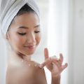 woman applying cream to her shoulder