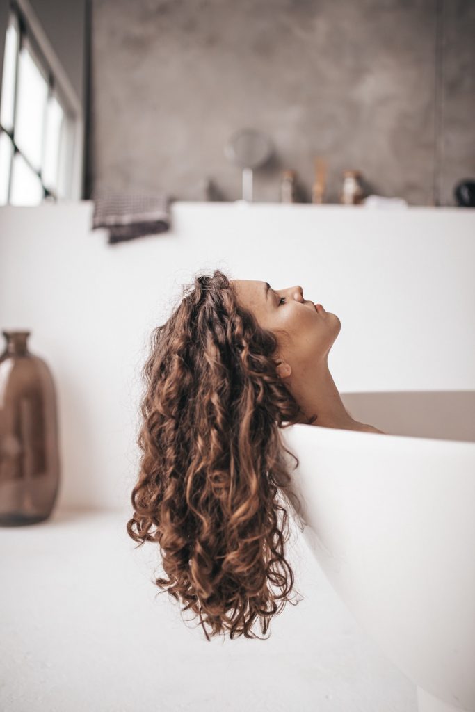 Woman in a bathtub with her long hair hanging over the side