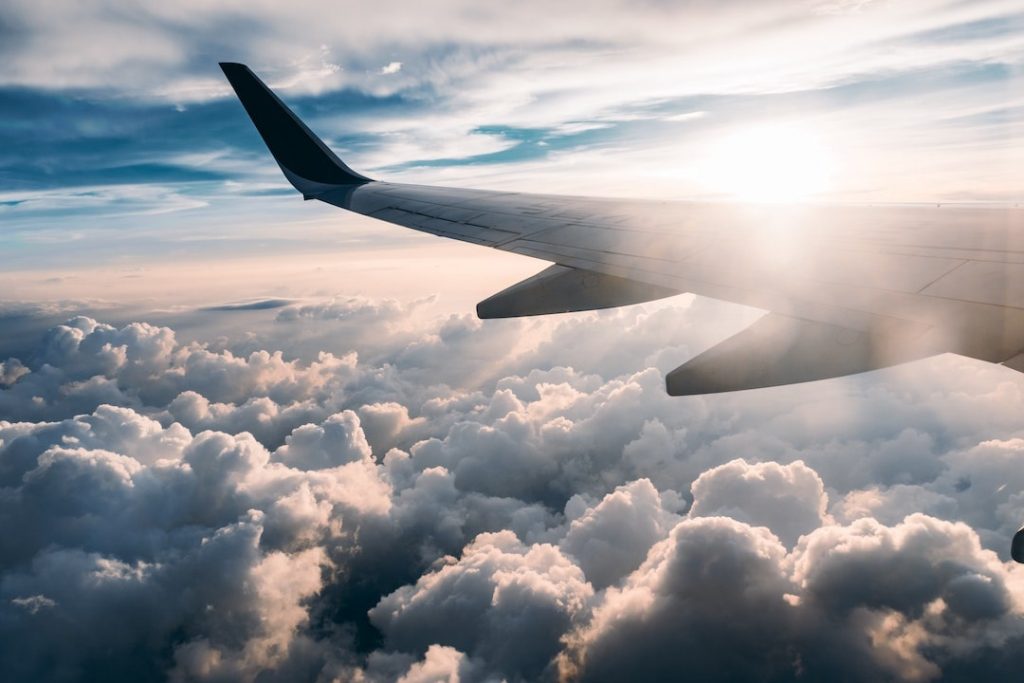 Plane wing over clouds with sun flare