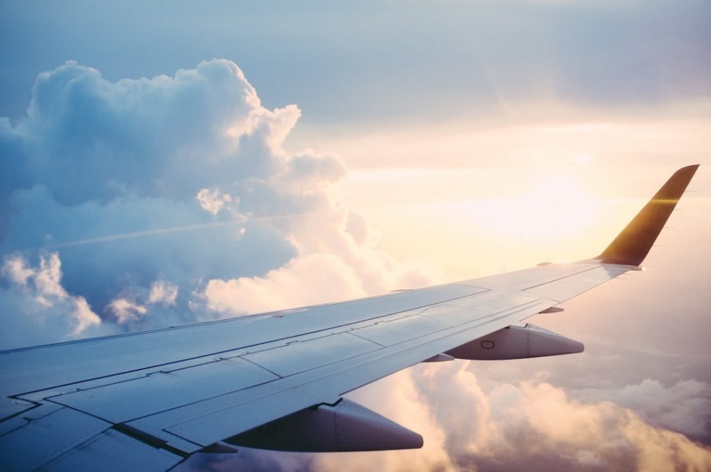 Plane wing with clouds and sun in the backround