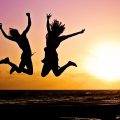 Silhouette of two people jumping at sunset