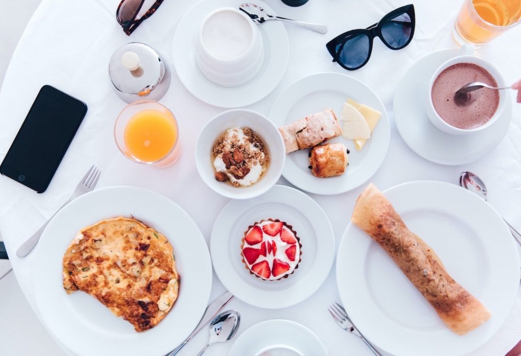 Table with spread of breakfast foods, orange juice, and coffee from above