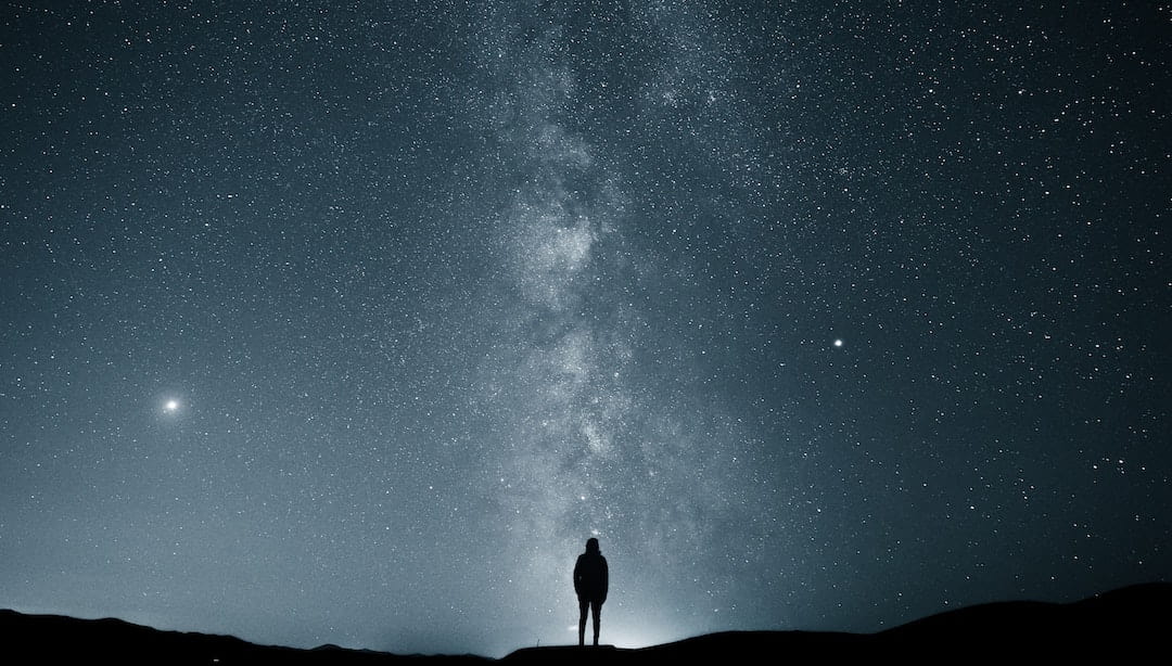 Person standing in front of a starry sky with the Milky Way in the background