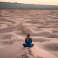 Woman sitting with her back facing camera on a sand dune