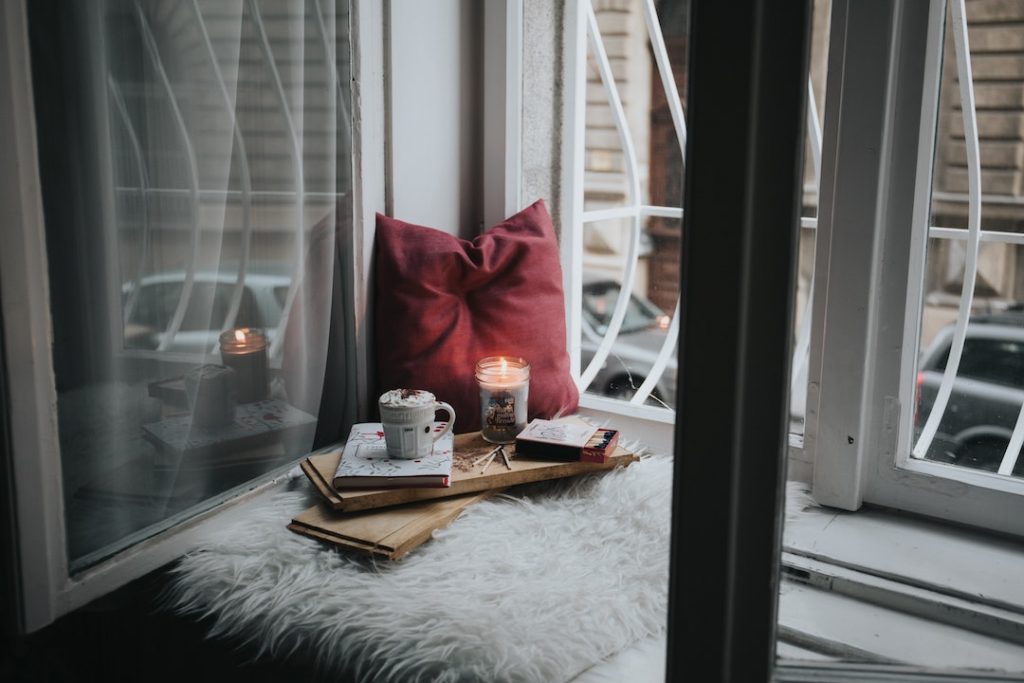 Cozy nook with a pillow and candle beside a window