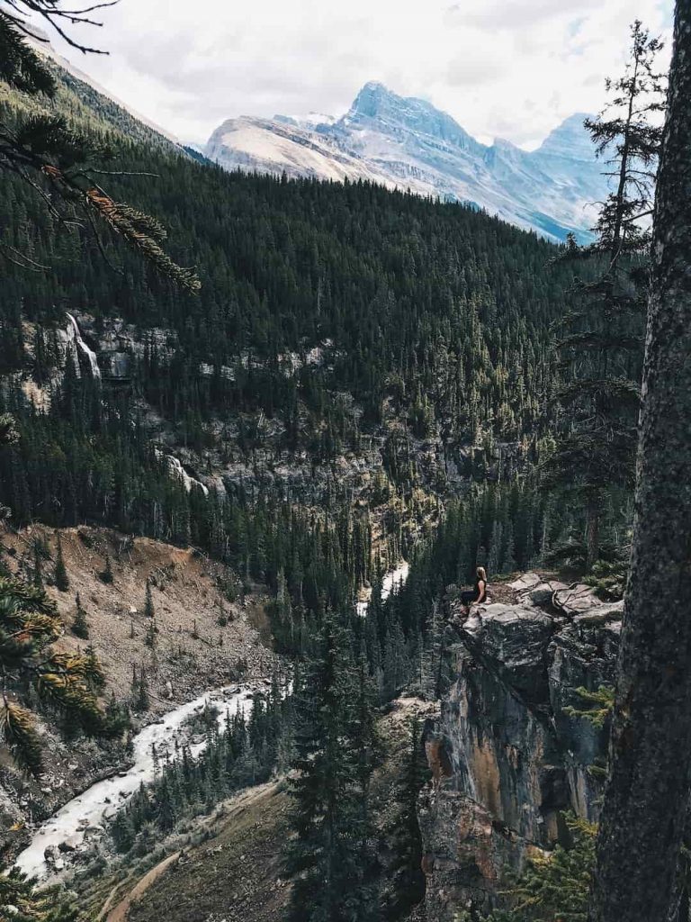 Woman sitting on the edge of a cliff overlooking the Canadian Rockies