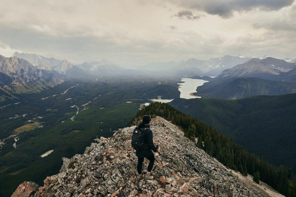 Person holding hiking poles standing at top of mountain in the Canadian Rockies